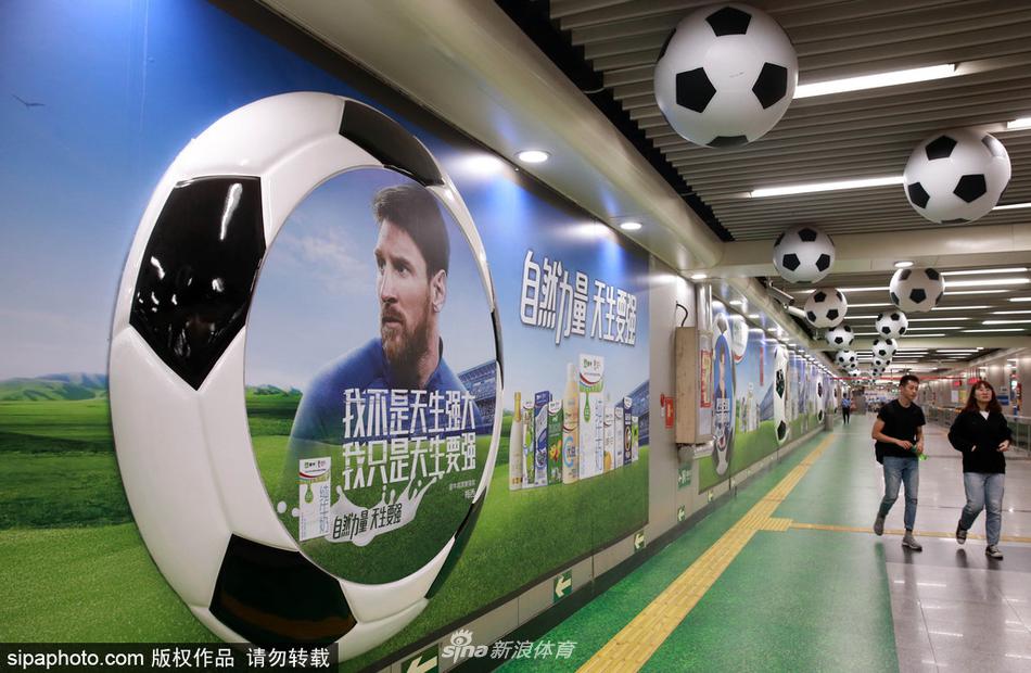 2018年5月31日，乘客从北京地铁站一号线某站台悬挂的数十只硕大的“足球”前经过。