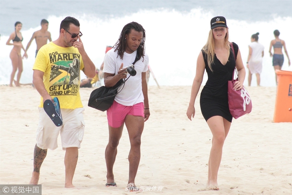 当地时间2017年12月28日，巴西，前荷兰足球运动员埃德加·戴维斯（Edgar Davids）和友人现身海滩。当天他与金发女郎沙滩漫步，身边男友人看上去像个大瓦“电灯泡”。